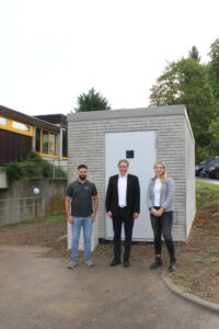Auf dem Bild: (v.l.) Kazim Bayramoglu, Bauleiter bei Deutsche Glasfaser, Gerhard Kuttler, Bürgermeister der Gemeinde Hochdorf und Ivana Zumbiel vom Zweckverband Landkreis Esslingen trafen sich vor dem PoP in der Jahnstraße in Hochdorf. (Bild: Lena Reich, Gemeinde Hochdorf)