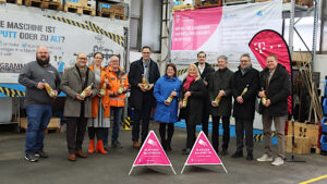 Pressetermin zum Glasfaserausbau in Denkendorf: Vertreter von Telekom, Kommune und Region stehen in einer Industriehalle vor Glasfaser-Banner und Baustellenschildern.
